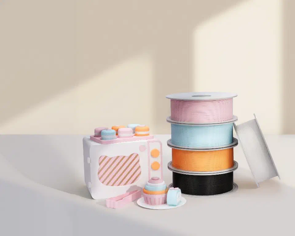 PLA Pure filament spools in pink, blue, orange, and black beside a 3D-printed toy kitchen play set