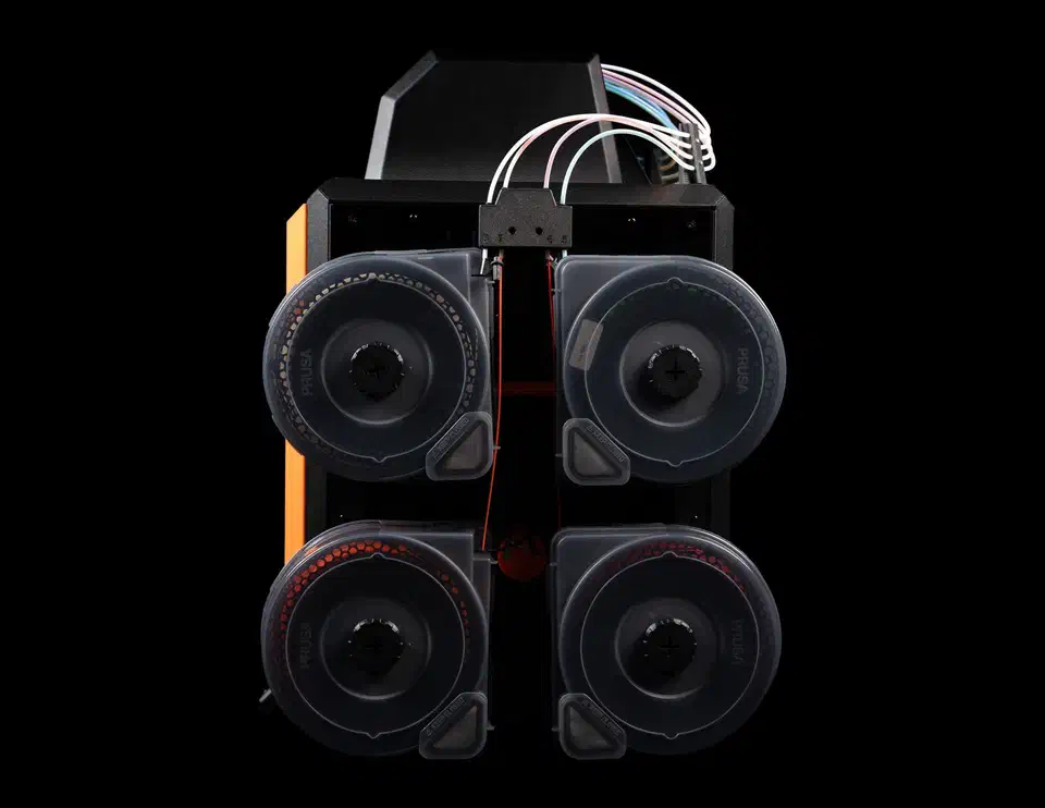 Rear of a Prusa CORE One with four sealed filament boxes mounted in a block and coloured PTFE tubes running up into the machine