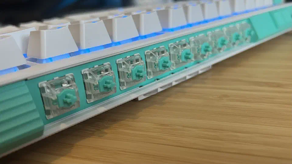 Row of clear-bodied teal Gateron analog switches clipped into the storage strip along the top edge of the G512 X