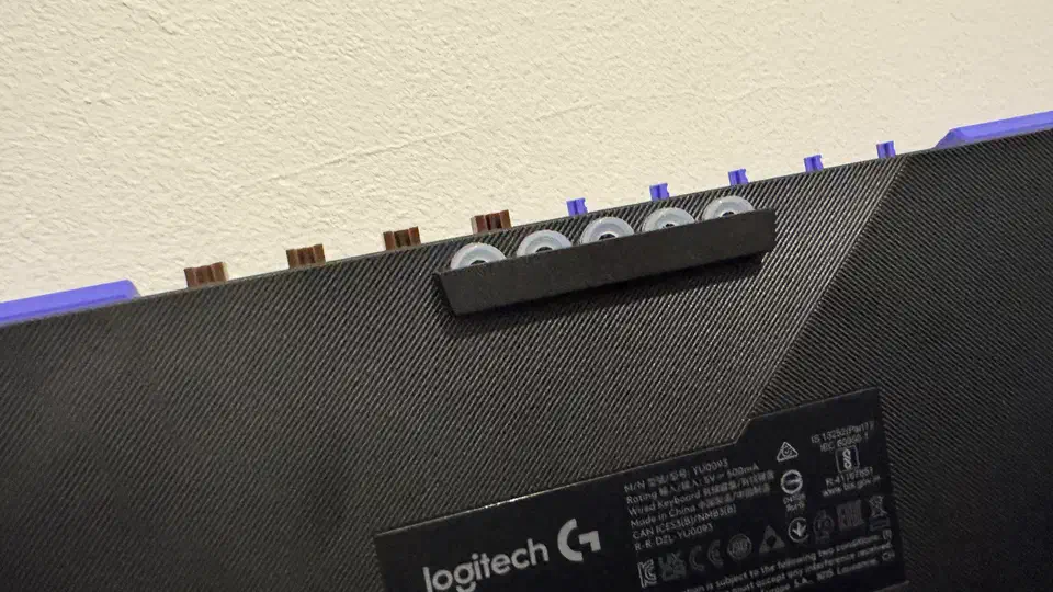 Underside of the G512 X with the compartment cover lifted, showing spare switches and white SAPP rings held in a row