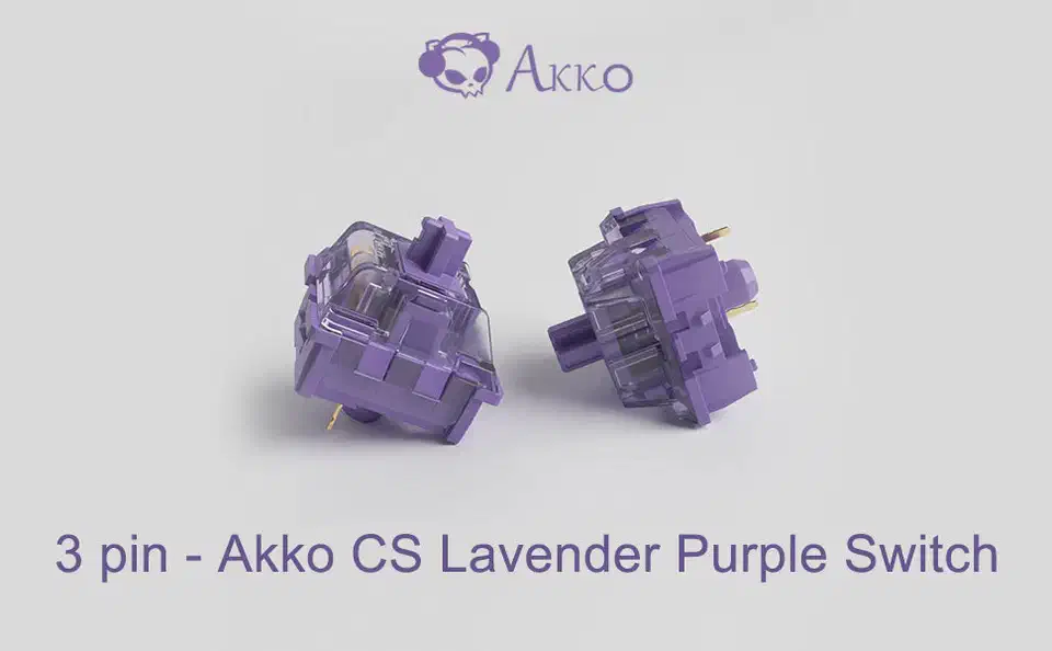 Two purple Akko CS Lavender 3-pin switches, one upright and one tipped to show two gold metal pins and a central plastic post