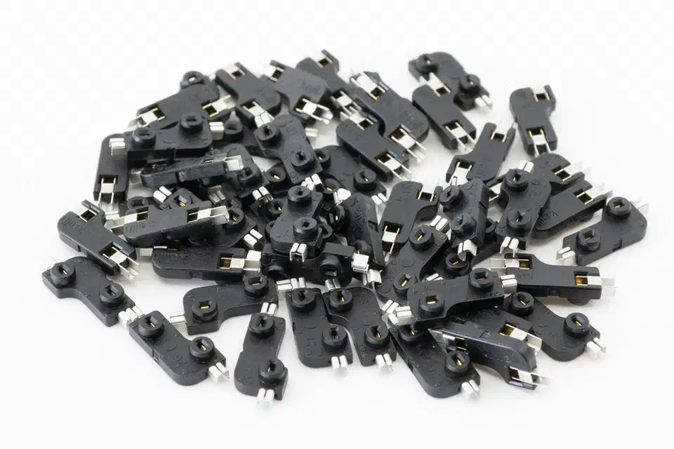 A pile of black Kailh hot-swap sockets on a white background, each with two silver solder tabs