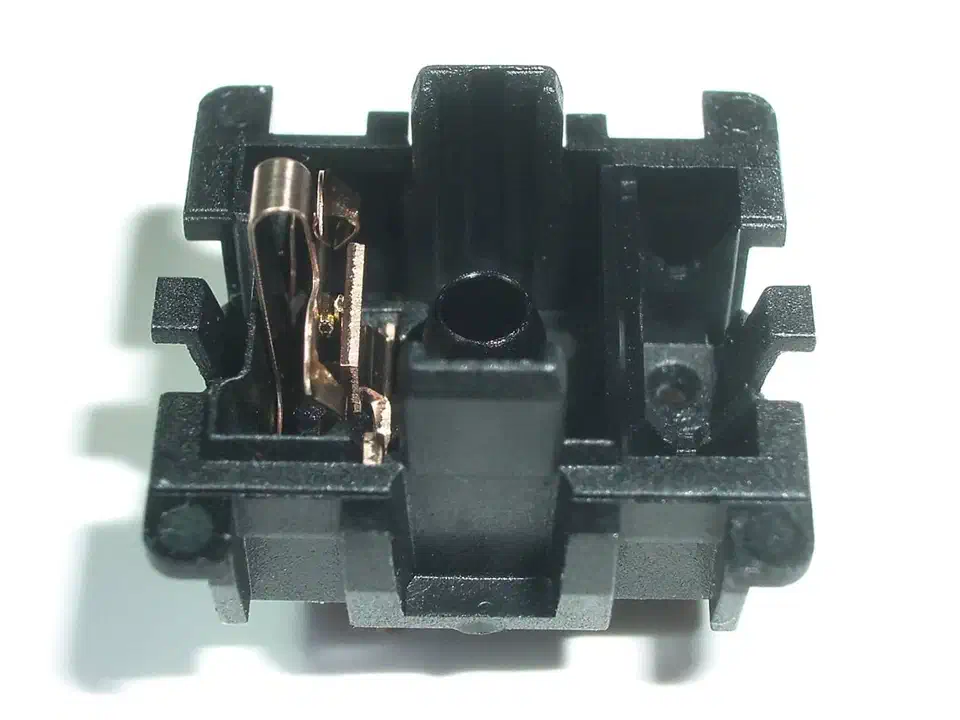 Opened Cherry MX mechanical switch housing showing the gold metal contact leaf that closes the circuit