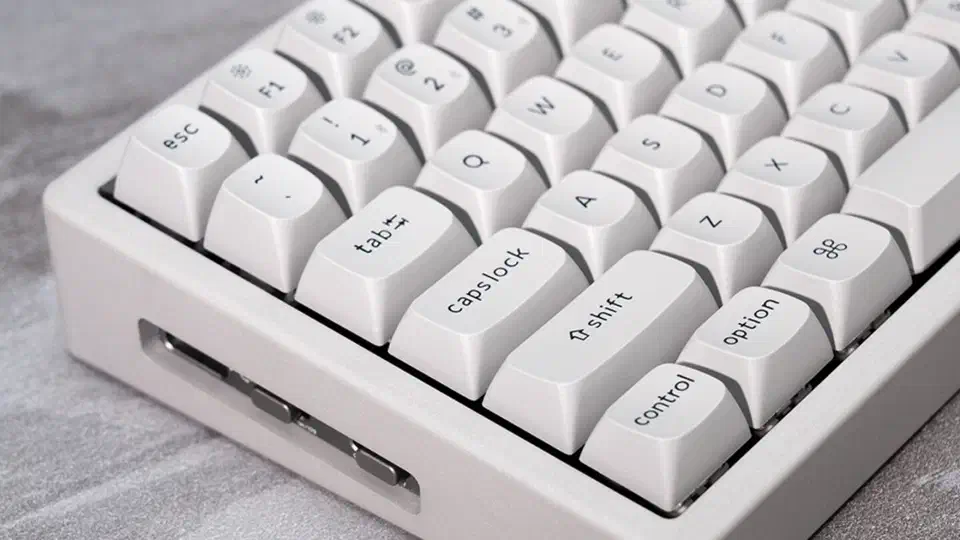 Close-up of the concrete edition’s cement-gray keycaps and marble-smooth pale grey shell with a side port cut into the case
