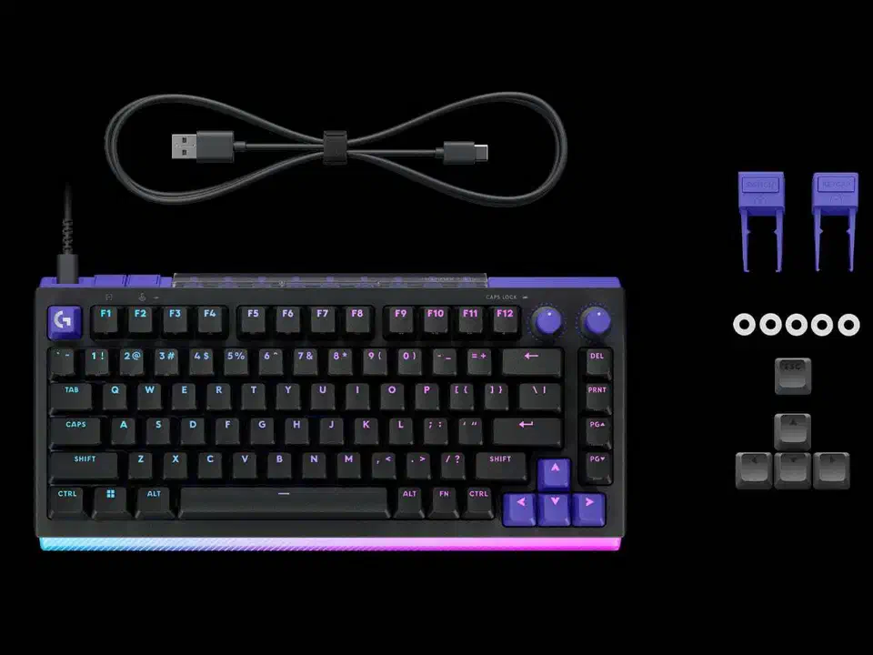 Top-down view of the black G512 X 75 keyboard beside its USB-C cable, two keycap pullers and spare keycaps, with violet accent keys on the arrow cluster