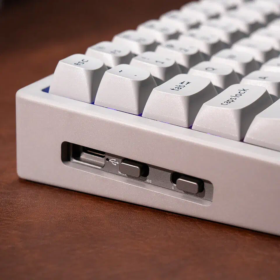 Close-up of the Keychron K2 HE Concrete Edition corner showing light grey matte PBT keycaps in OSA profile above the grey body and its side switches