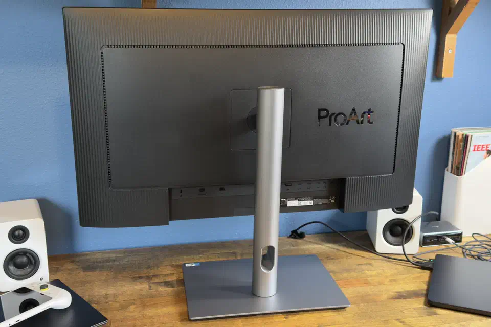 Rear view of the ProArt PA32QCV showing the ribbed back panel, the ProArt badge, the silver stand pillar and the recessed port bay