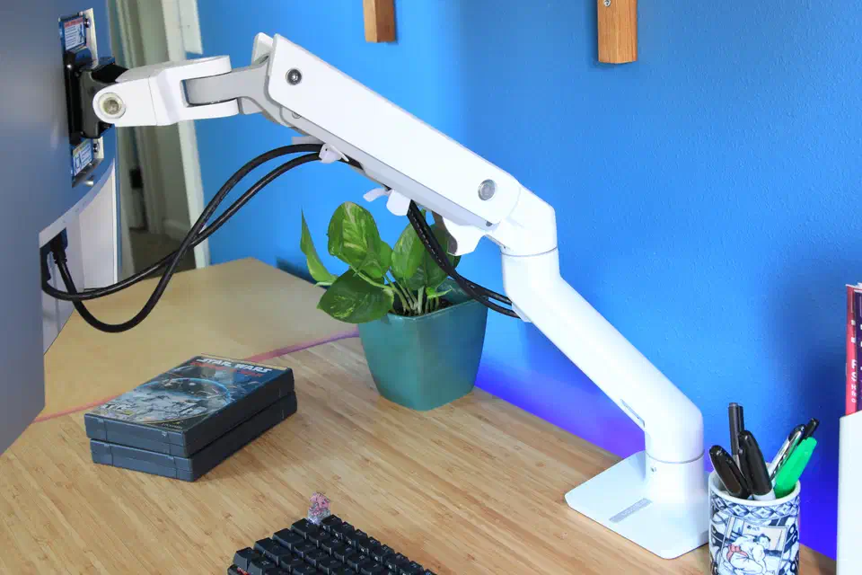 White Ergotron HX single-monitor arm clamped to a desk edge with cables routed along the arm, no monitor attached