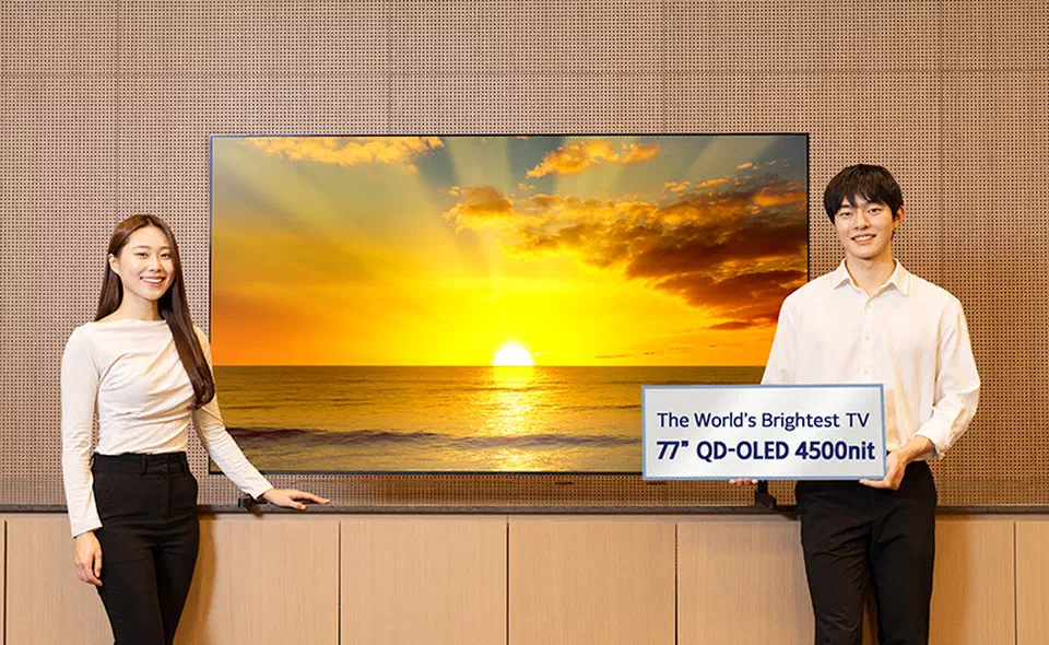 Samsung Display staff standing beside a large 2026 QD-OLED TV panel on show at CES, rated 4,500 nits peak brightness