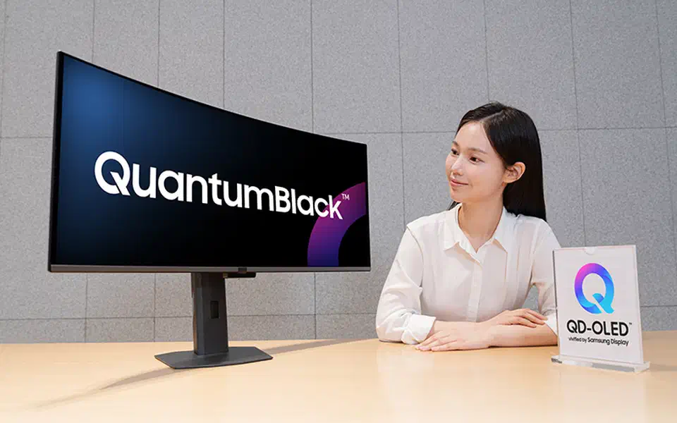 Samsung Display QuantumBlack coating on a QD-OLED monitor panel reflecting a window, showing the darker anti-reflective surface