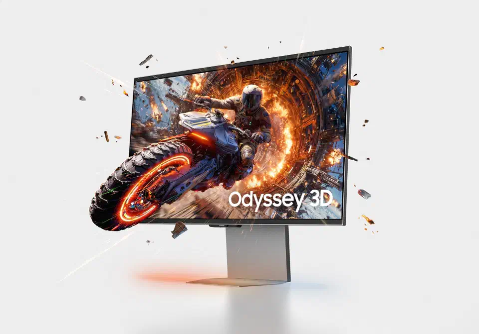 Samsung Odyssey 3D G90XH monitor on a slim silver stand, screen showing a motorcycle rider bursting out of the panel