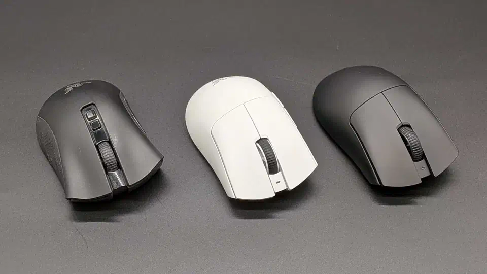 Three Razer wireless gaming mice lined up on a grey desk mat, an older black model on the left beside a white and a matte black flagship