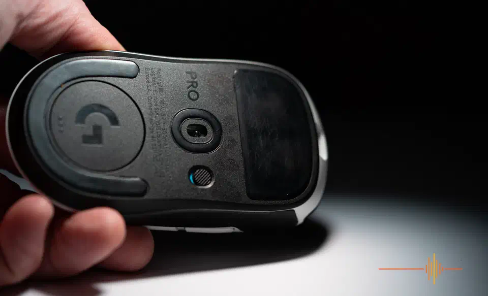 Underside of the Logitech G Pro X2 Superstrike held in a hand, showing the sensor, PTFE skates and a single small power switch with no DPI button