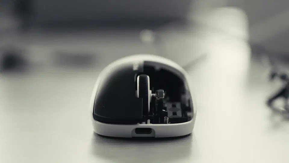 Logitech G Pro X2 Superstrike with its button plate lifted away, exposing the circuit board and coil hardware under the main buttons