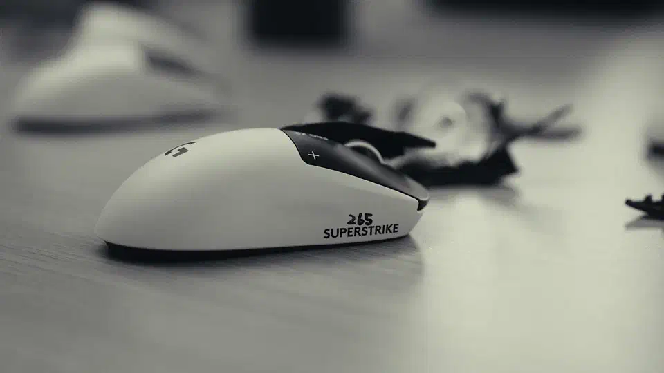 White Logitech G Pro X2 Superstrike with a black top plate resting on a light desk, shown from a low three-quarter front angle