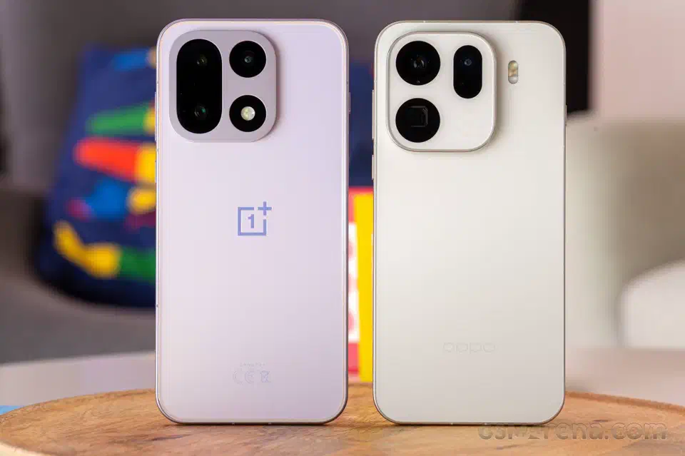 OnePlus 15 in lilac beside a white Oppo phone, both standing rear-facing on a wooden table