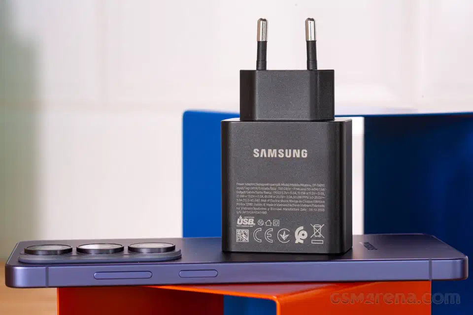 Samsung 60W power adapter resting on the flat side edge of a Galaxy S26 Ultra, showing how thin the phone frame is