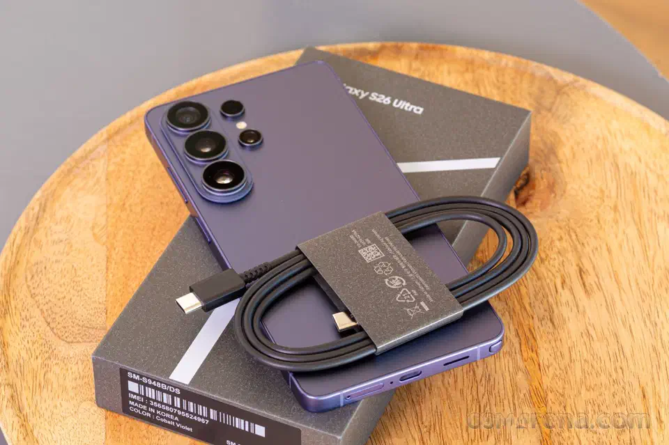 Galaxy S26 Ultra lying face-down on its retail box with a coiled USB-C cable, the box label reading Cobalt Violet