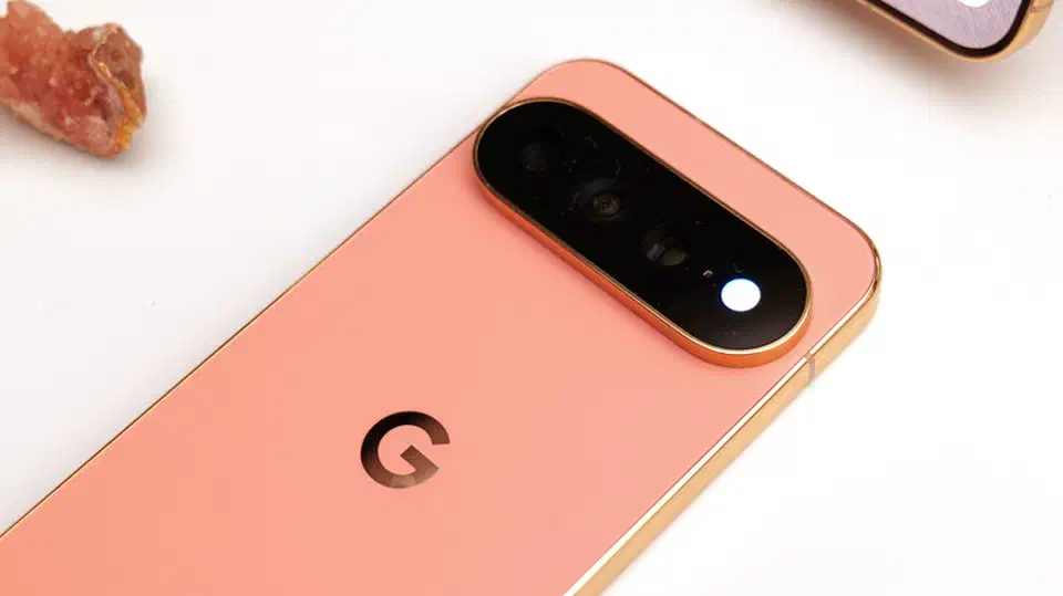 Close-up of a coral Pixel 11 Pro&rsquo;s rear camera bar with the flash lit bright white where the HiLight LED ring sits