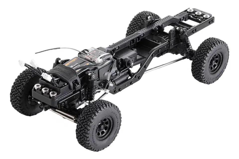 Bare FMS FCX18 II rolling chassis with black ladder rails, low-mounted gearbox, electronics tray, shocks and four all-terrain tires