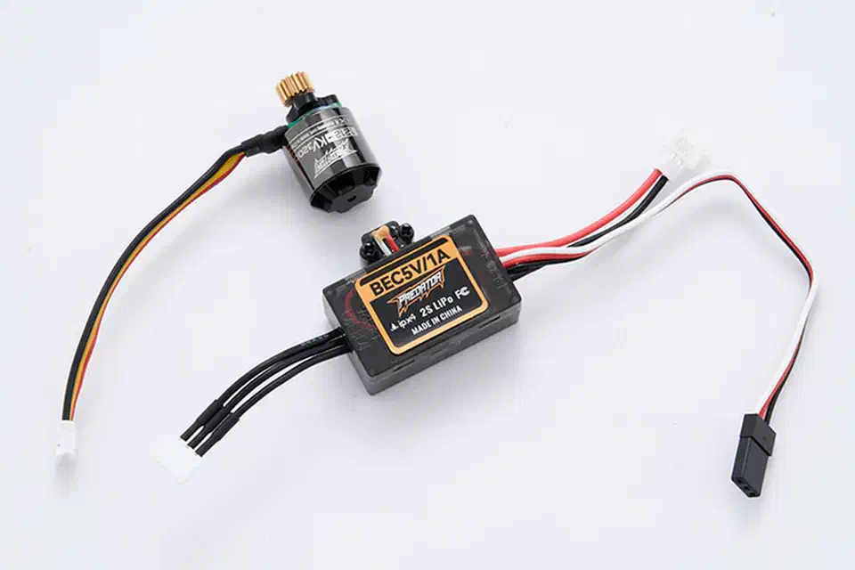 Brushless outrunner motor wired to a small FOC ESC with an integrated receiver and BEC, laid out on a light surface