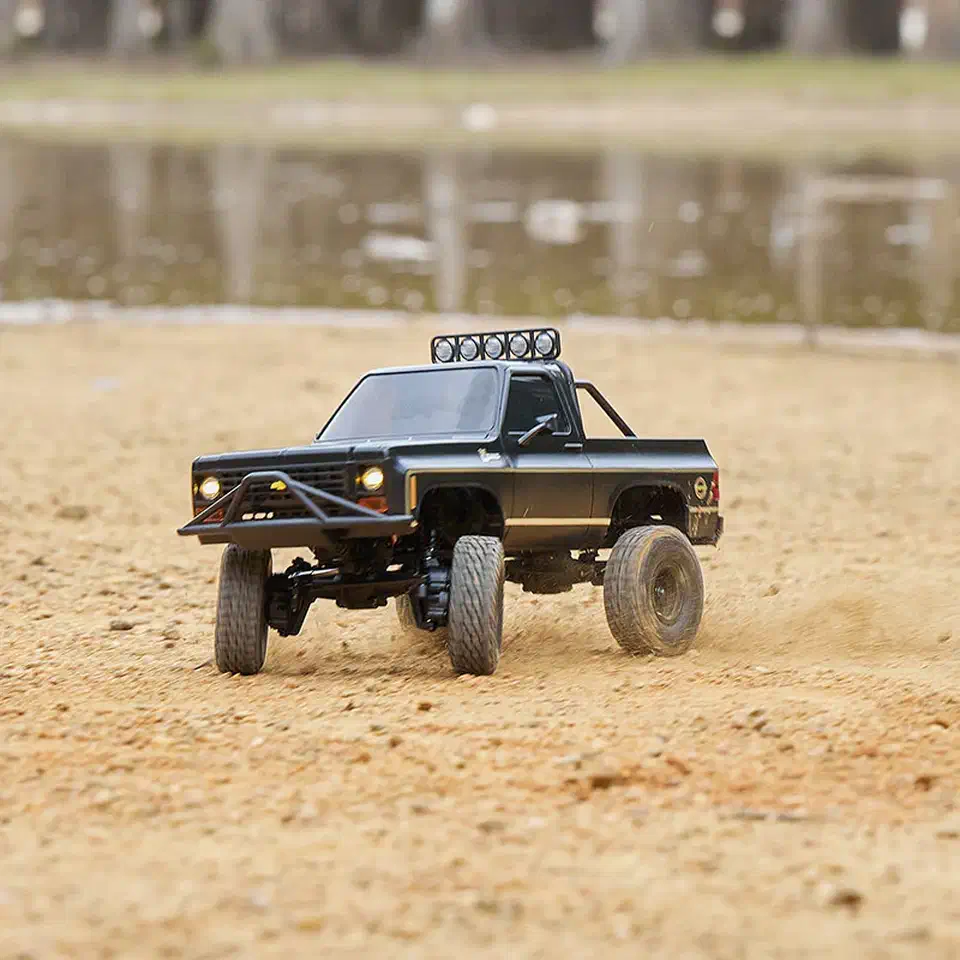 FMS FCX24 K5 Blazer 1/24 scale RC crawler driving across sandy ground with front wheels articulating
