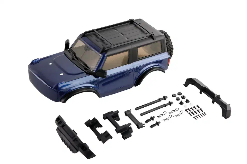 Blue painted FCX24 body shell laid out beside its black bumpers, body posts, mounting clips and screws