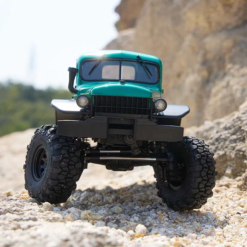 FMS FCX24 Power Wagon 1/24 crawler with a green hard body and black bumper climbing rocks