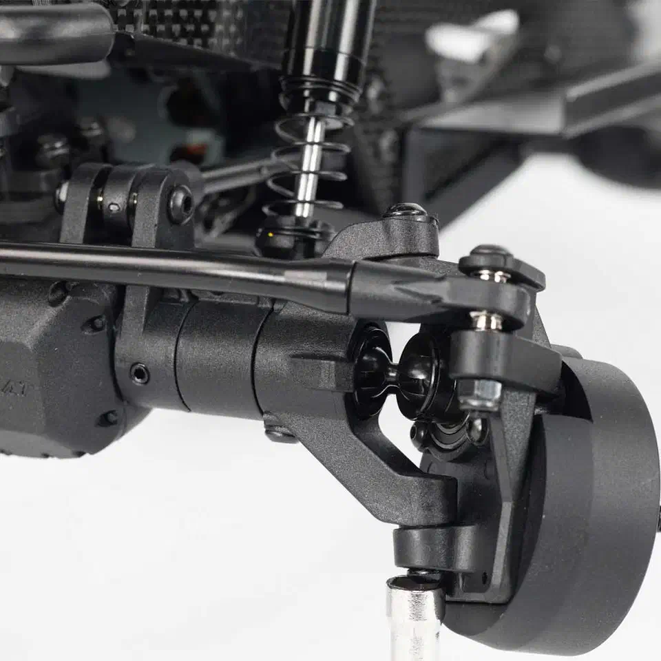 Close-up of the Redcat Vertex-10W front portal axle, black suspension link, and coil-over air shock mounted to the carbon-fiber chassis